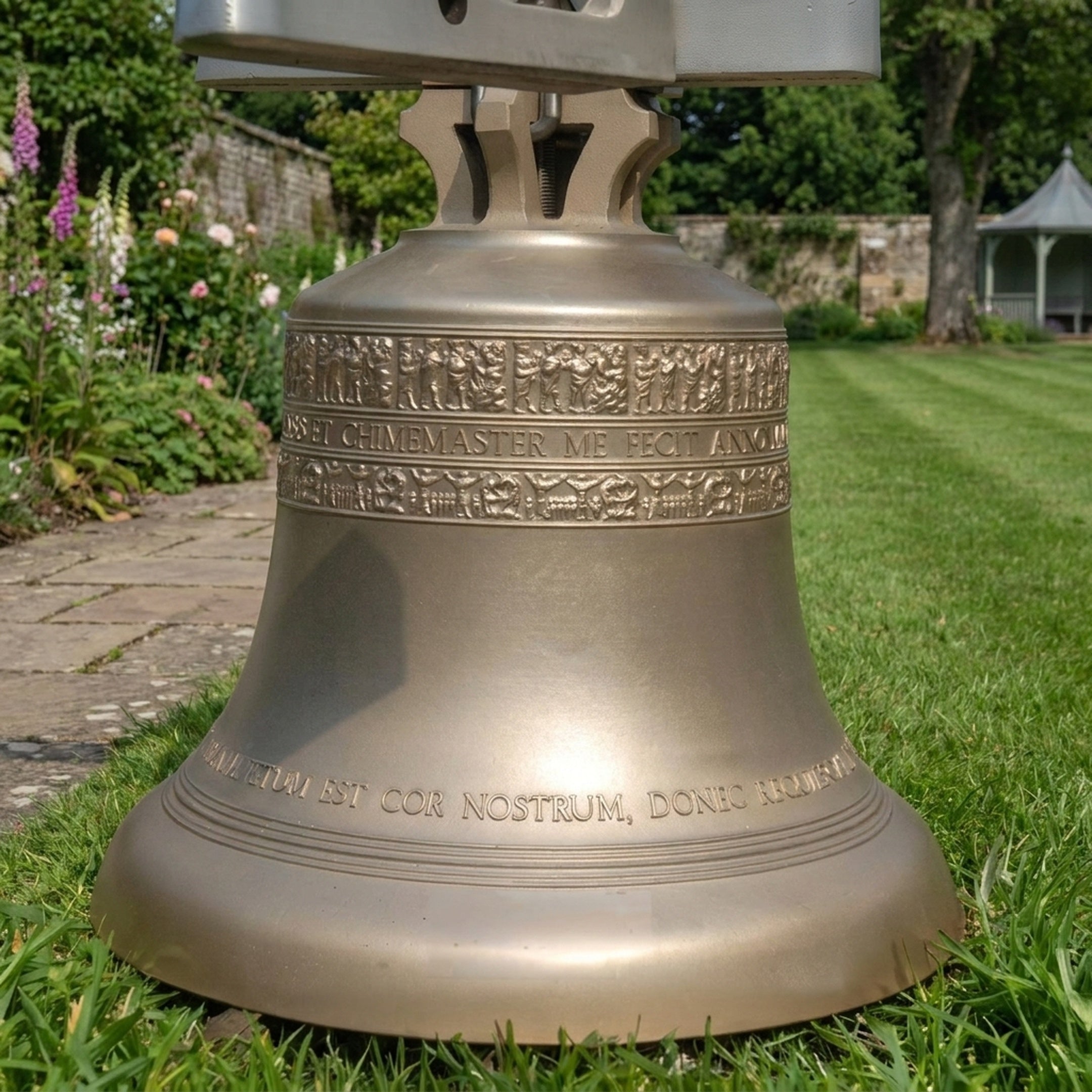 Traditional Church Bell Bronze Sculpture 100cm by Giant Sculptures, golden-brass finish with relief frieze and Latin inscription, displayed on a garden lawn.