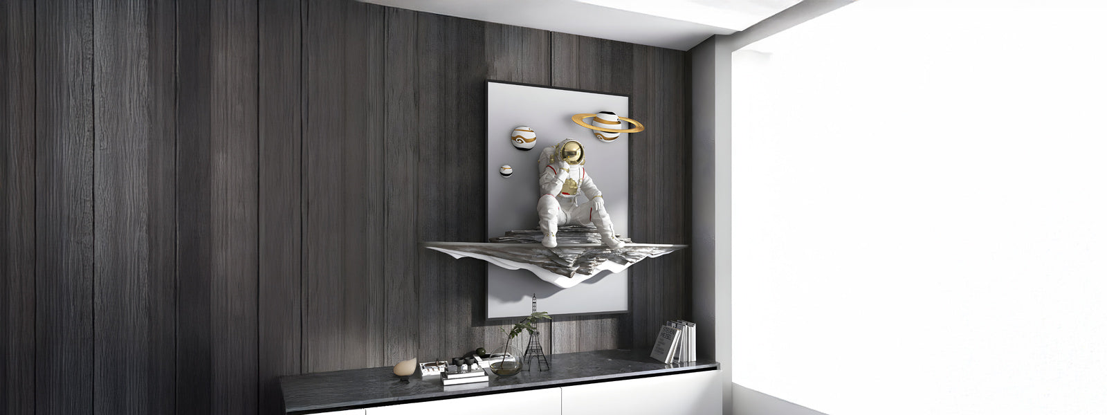 A modern art piece depicting a reflective astronaut sitting on an abstract metallic surface, with floating planets above. The artwork is set against a dark wood-paneled wall above a minimalist cabinet.