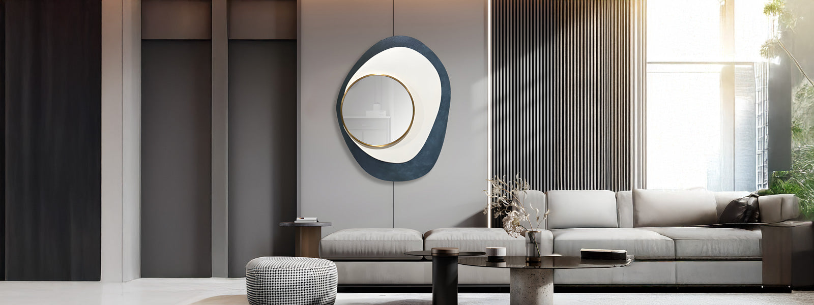 Modern living room with a neutral-toned sofa, decorative round mirror, and minimalist furniture. Sunlight streams through large windows, casting warm light on the sleek, stylish decor.