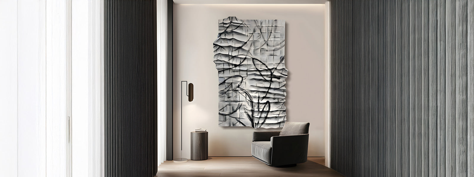 A minimalist hallway with dark wood paneling features a modern gray armchair and a cylindrical side table. A large abstract sculpture with a textured surface hangs on the white wall at the end.