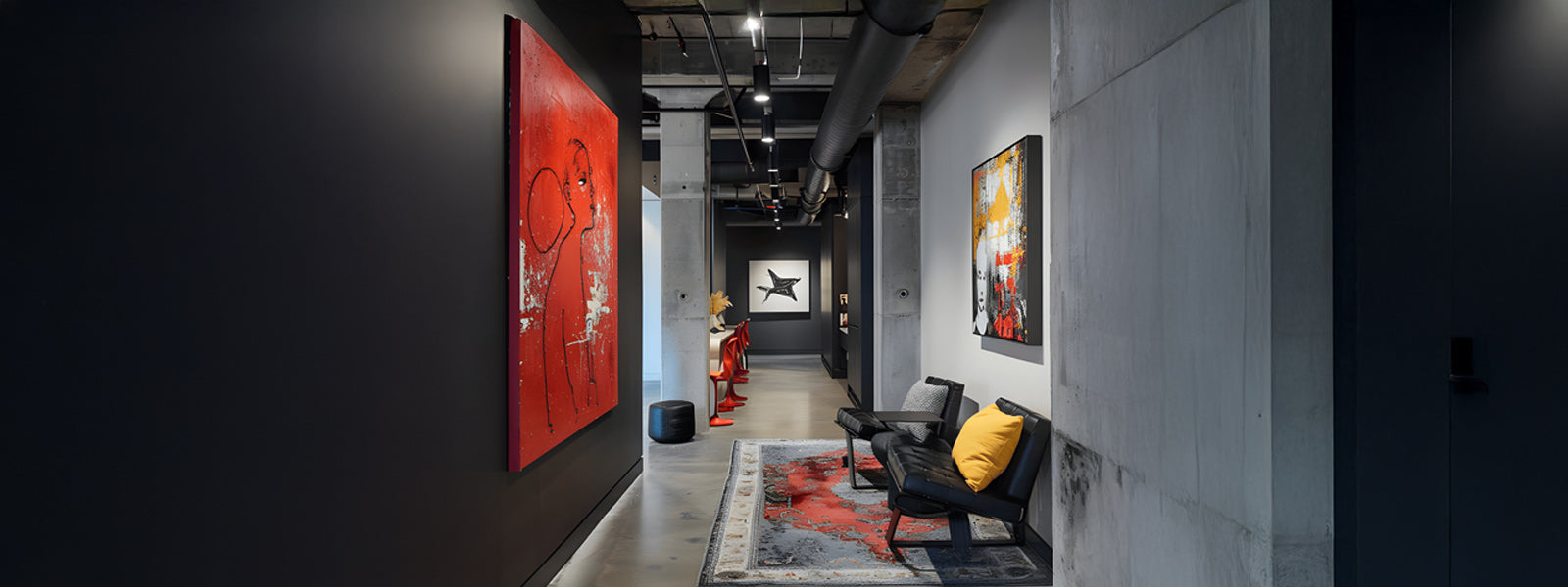 Art gallery hallway with modern paintings on dark walls. Two black chairs with a yellow cushion sit on a patterned rug. The floor and ceiling have an industrial style.