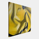 The Smile Fragment Abstract Canvas Wall Art by Giant Sculptures displays bold black and dark green curved lines on yellow, presented on a thin canvas with a white background and shown from an angled side view.
