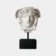 The Medusa Head Marble Sculpture - 80cm by Giant Sculptures features snake hair, wing details, and a calm expression on a black base. This elegant white sculpture stands out as a striking decor piece against a plain white background.