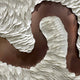 The Riverine Flow Pearl White Textured Triptych Wall Art by Giant Sculptures features layered, flowing white ovals on a brown background, creating a striking modern design reminiscent of feathers or scales.