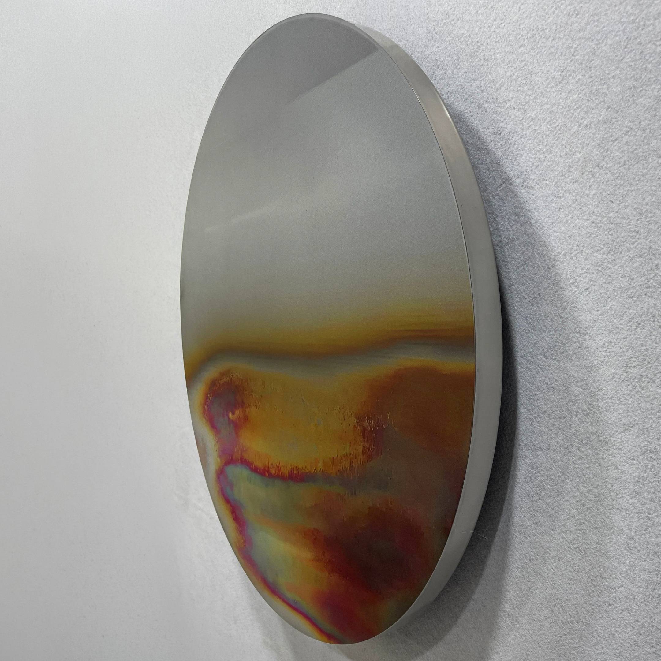 The Iridia Halo I Abstract Acrylic UV Wall Art by Giant Sculptures is a round, metallic disc with vibrant yellow, orange, red, and purple patterns—a striking modern minimalist piece for your wall.