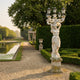 Classical Woman Five-Arm Lamp Marble Sculpture 300cm by Giant Sculptures, draped figure holding lanterns aloft on a pedestal beside a formal garden pond.