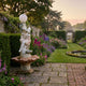 Giant Sculptures 240cm Figure Lamp on Column Marble Sculpture with a classical woman, terracotta scalloped basin and globe lamp in a walled flower garden.