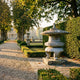 Giant Sculptures 80cm Japanese Pagoda Stone Lantern in weathered grey granite, set on a stone plinth beside a manicured hedge in a formal garden pathway.