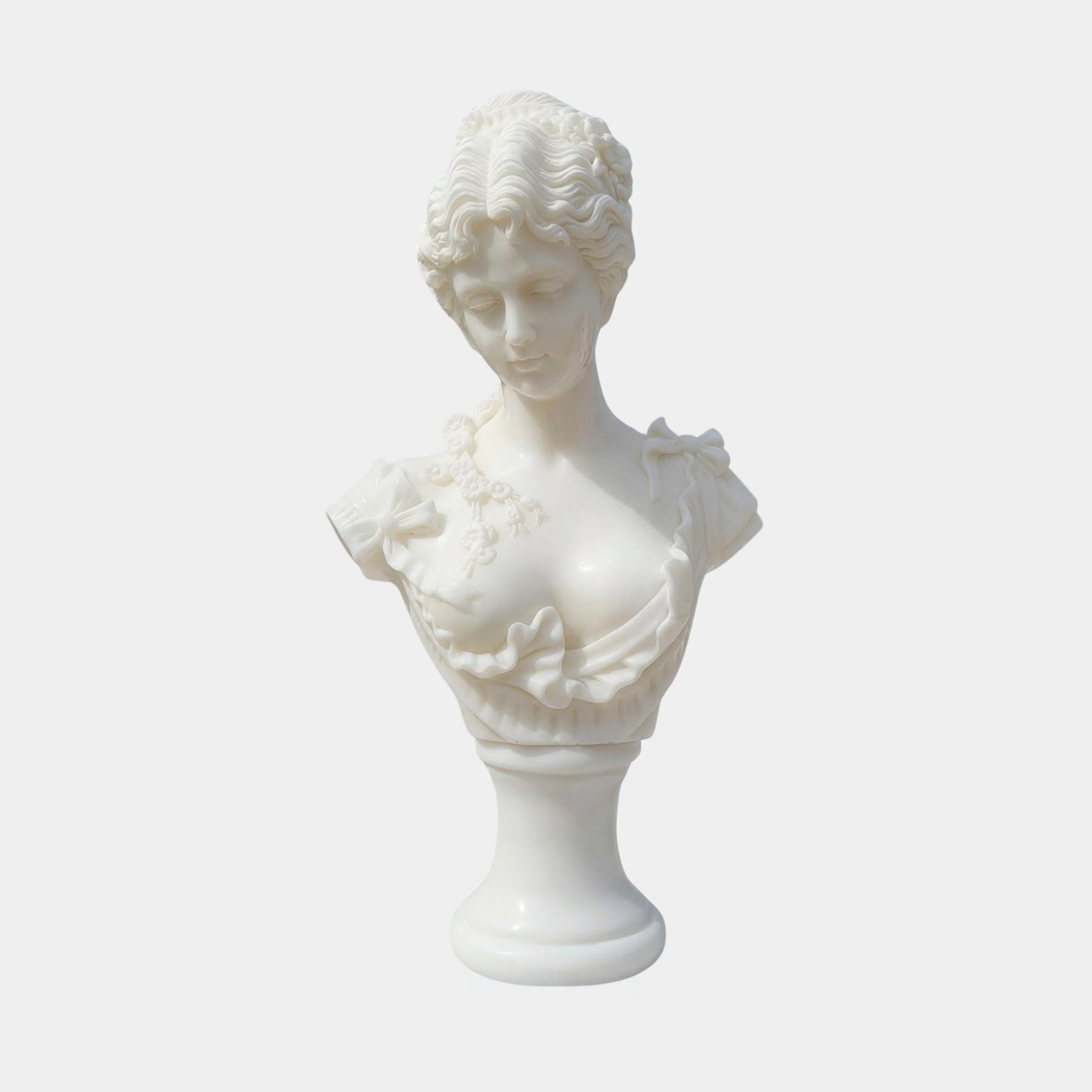 The Classical Youth Marble Bust Sculpture by Giant Sculptures (65cm) features a white marble bust of a woman with wavy hair and a ruffled floral dress, gazing downward, set against a plain white background.