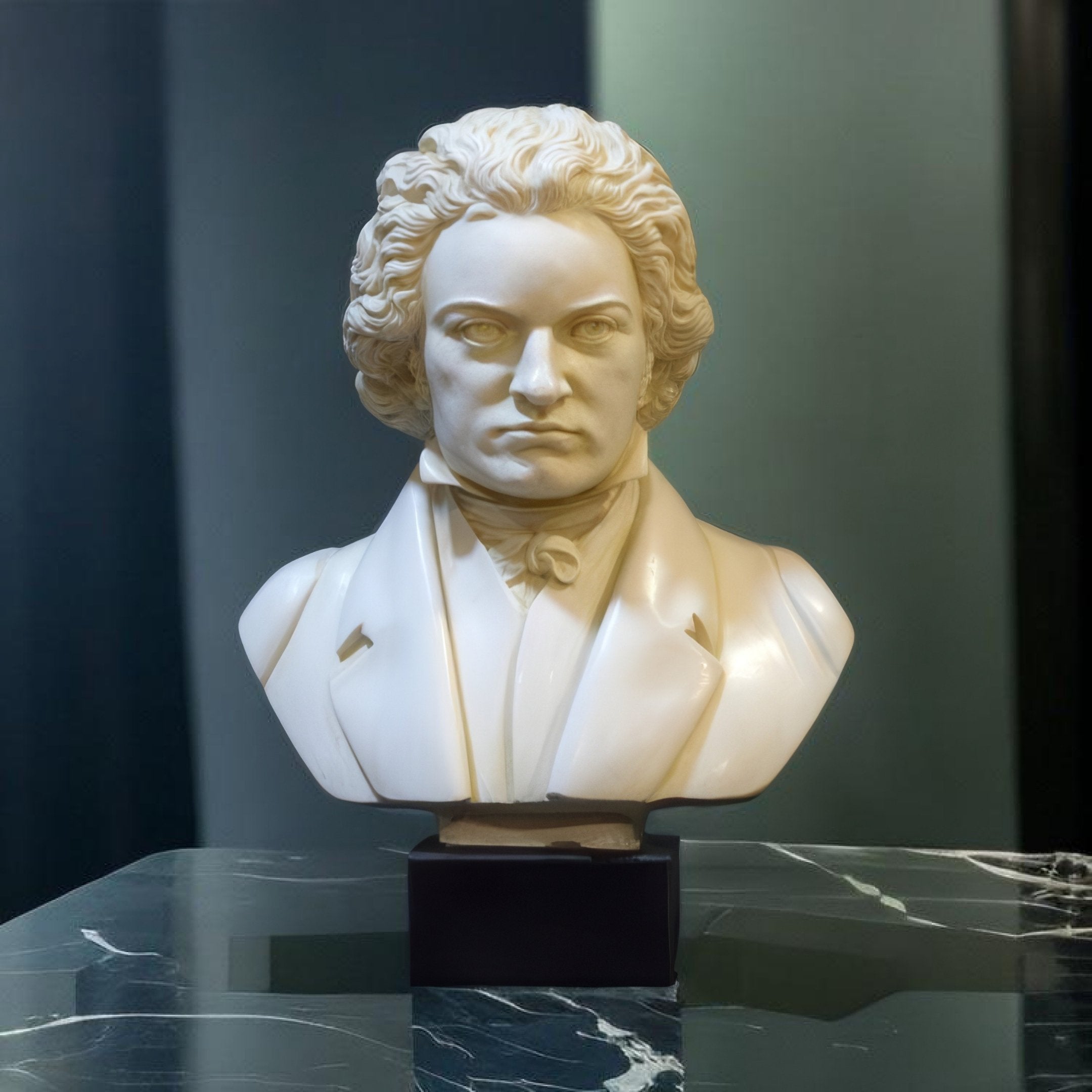The Beethoven Marble Bust Sculpture - 60cm by Giant Sculptures features a white marble bust of a curly-haired man with a serious expression, in a cravat and coat, set on a black pedestal atop marble against a dark, blurred background.