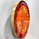Side-angle view of the Galaxia Sun Crystal Porcelain LED Wall Art showing its slim brushed gold frame and glossy amber-orange sun motif against a white wall.