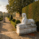 Giant Sculptures Egyptian Sphinx 110cm white marble statue in recumbent pose with nemes headdress on a plinth beside manicured hedges in a formal garden.