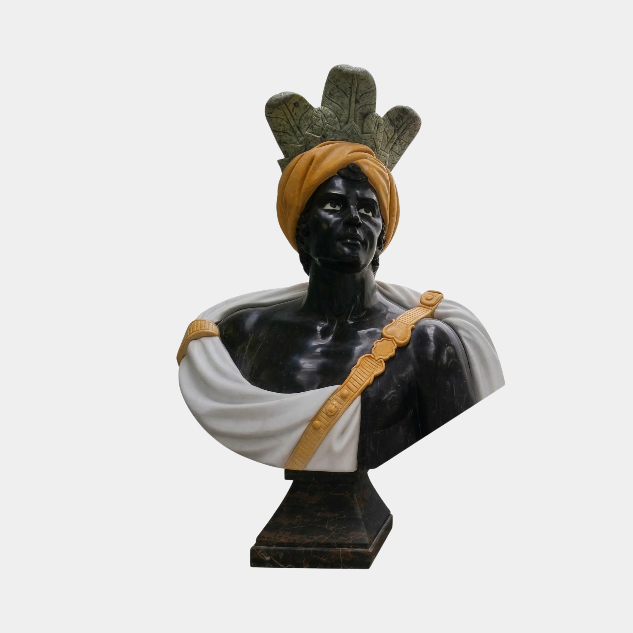 The Moorish Feather Turban Marble Bust Sculpture (85cm) by Giant Sculptures is a luxury art piece featuring a man with a gold feather turban, leaf headdress, and white-and-gold sash on a dark pedestal against a white background.