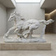 The Running Horse White Marble Outdoor Sculpture - 120cm by Giant Sculptures stands on a stone pedestal in a minimalist modern gallery with concrete walls and a large skylight above.