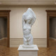 The Female Marble Torso Sculpture - 80cm by Giant Sculptures, carved from natural white marble, stands on a pedestal in a gallery with wooden floors. The partially draped figure's head and one arm are veiled by flowing fabric.