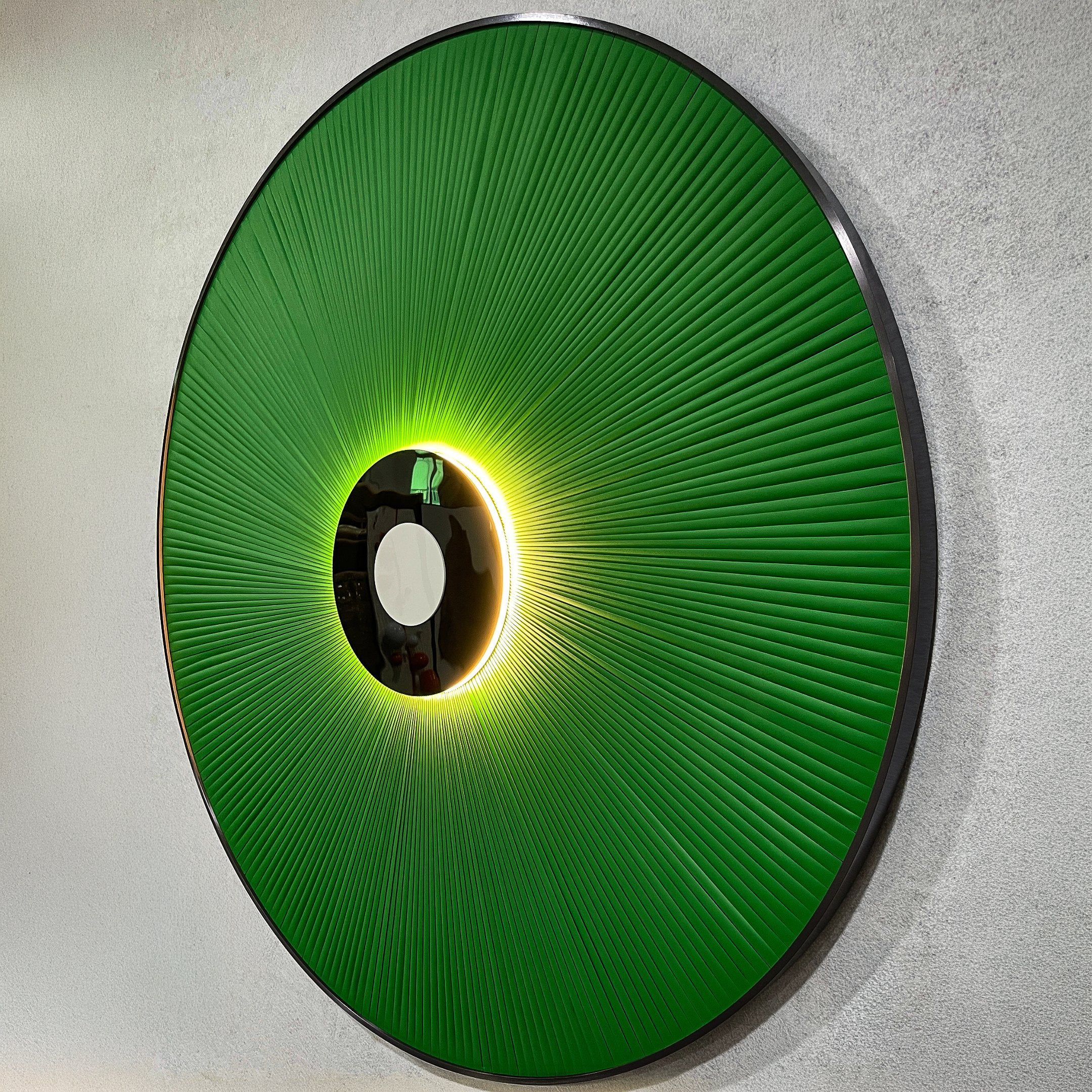 Vanguard Jade Surge Leather 3D LED Wall Art shown at an angle, with jade-green leather rays radiating from a black disc, backlit by warm LED glow.