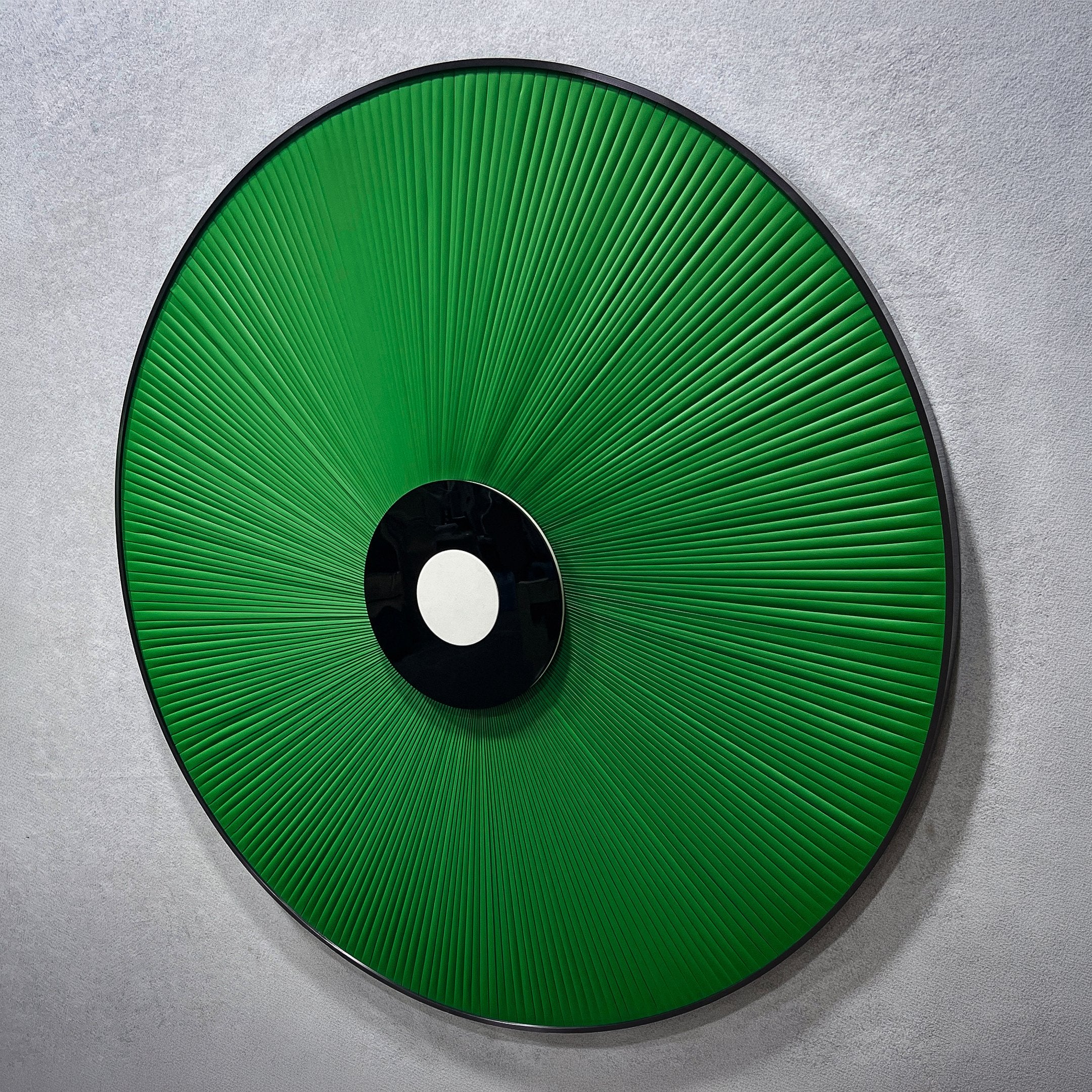 Vanguard Jade Surge Leather 3D LED Wall Art by Giant Sculptures shown at an angle, with jade-green leather rays radiating from a black-and-white central disc on a pale wall.