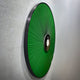 Side-angle view of the Vanguard Jade Surge Leather 3D LED Wall Art, showing jade-green leather rays radiating from a black-and-white central disc on a pale wall.