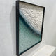 Side angle view of the Seravelle Mist Blue Gradient Layered 3D Paper Wall Art in a black shadow box frame, showing the textured wave of white and teal paper forms.