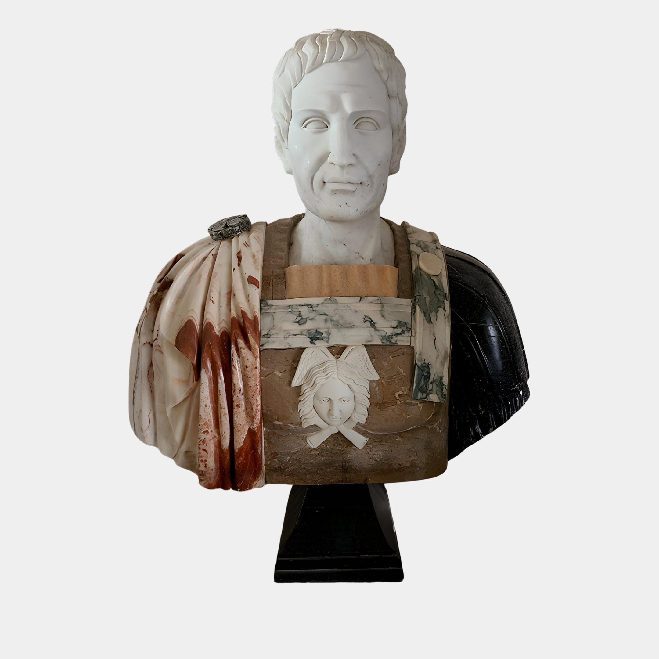 The Giant Sculptures Roman General Marble Bust Sculpture (85cm) features a short-haired general in a detailed multicolored cloak, standing on a black pedestal with carved face and crossed swords, showcasing exquisite marble craftsmanship.