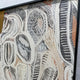 Close-up angled view of the Aurista Botanical Flow Abstract Cotton Spray Wall Art showing raised beige and black leaf forms over a gold ground in a black frame.