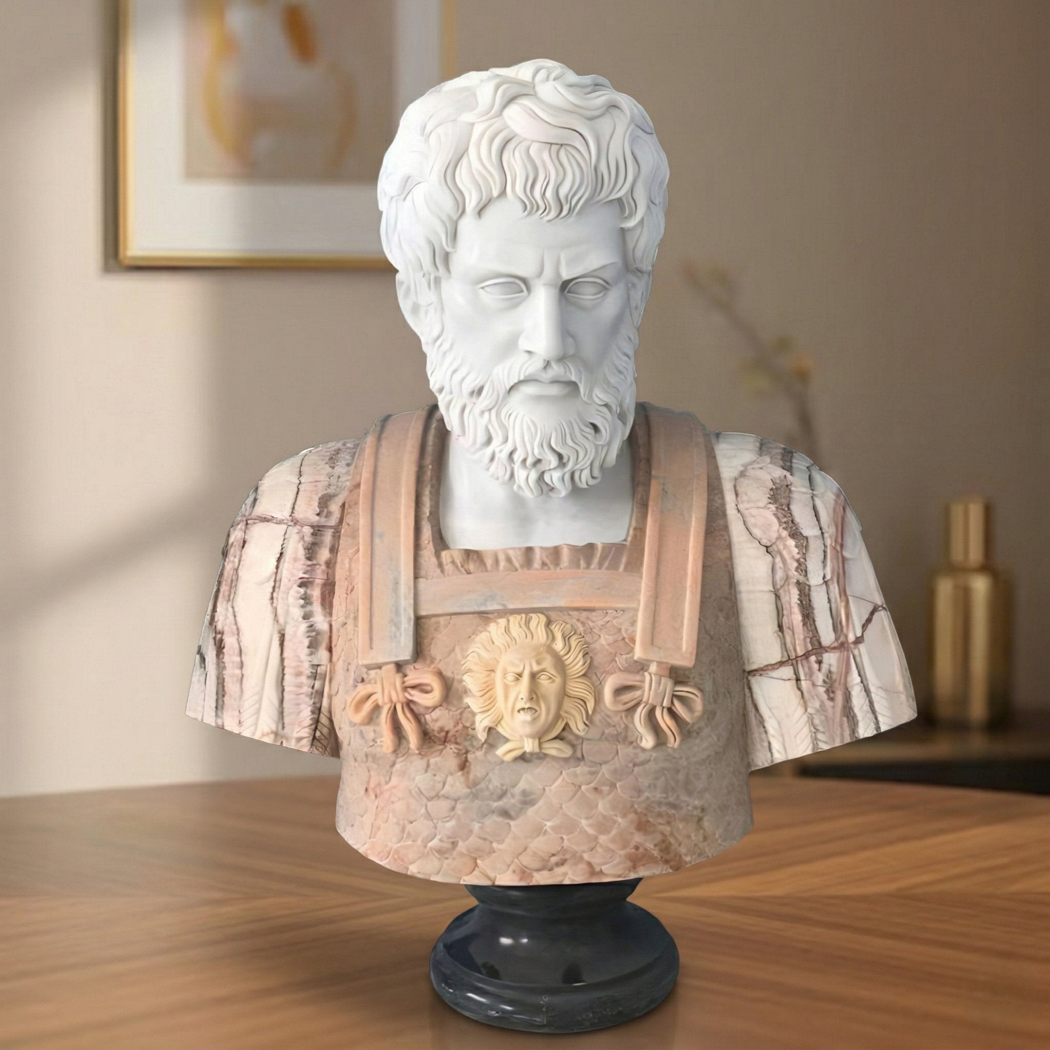 The Marcus Aurelius Marble Bust Sculpture (75cm) by Giant Sculptures depicts a bearded man in ornate armor with a Medusa head, and is displayed on a wooden table with framed art and a gold vase in the softly lit background.