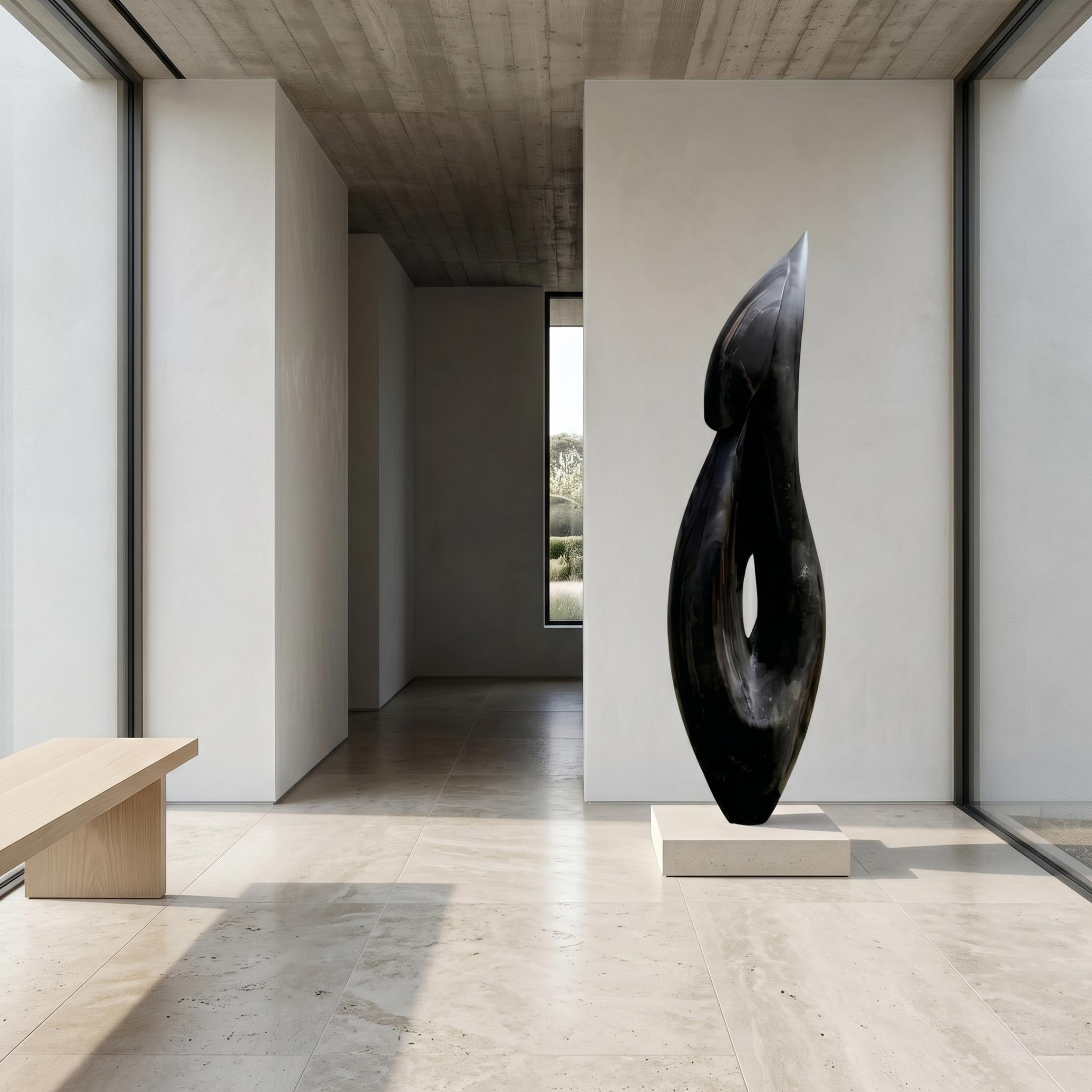 Abstract Flame Marble Sculpture by Giant Sculptures in black marble on a stone plinth, displayed in a minimalist concrete hallway beside a pale wood bench.