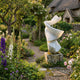 Abstract Twisted Form Marble Sculpture 80cm by Giant Sculptures, white spiralling stone on a weathered plinth in a cottage garden with roses and foxgloves.