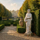 Giant Sculptures Spring Maiden Marble Sculpture 160cm holding fruit, set beside a clipped hedge in a formal garden with urn, reflecting pool, and pavilion.