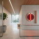 Onyx Flame Glow Acrylic 3D LED Wall Art by Giant Sculptures mounted in a minimalist reception with fluted glass desk, wood-slat ceiling and courtyard view.