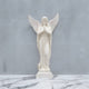 The 220cm Prayerful Angel Marble Outdoor Sculpture by Giant Sculptures stands gracefully with clasped hands, wings, and a flowing robe on a matching marble surface against a plain gray background, exuding serenity and elegance as a garden centrepiece.