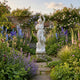 Giant Sculptures Female Figure with Pedestal Marble Sculpture 210cm in a walled English garden, surrounded by delphiniums, foxgloves, and climbing roses.