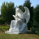 Giant Sculptures Tranquil Reading Angel Marble Outdoor Sculpture, standing 150cm tall, enhances a sunlit garden with lush green trees. Its serene pose and intricate details exude elegance and tranquility, creating an enchanting scene with its gently spread wings.