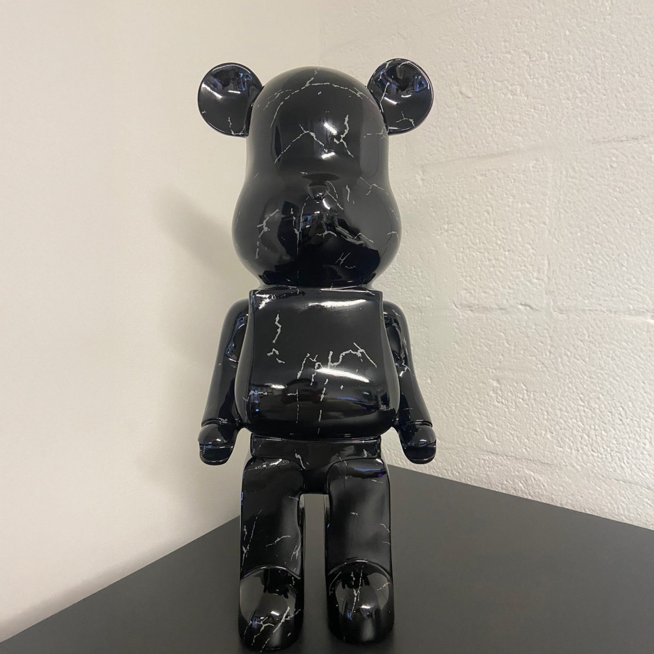 The Giant Sculptures Black Stone Bear Sculpture - 50cm (Ex Display) features elegant white marbling and stands out on any surface, making it a striking addition to modern interiors.
