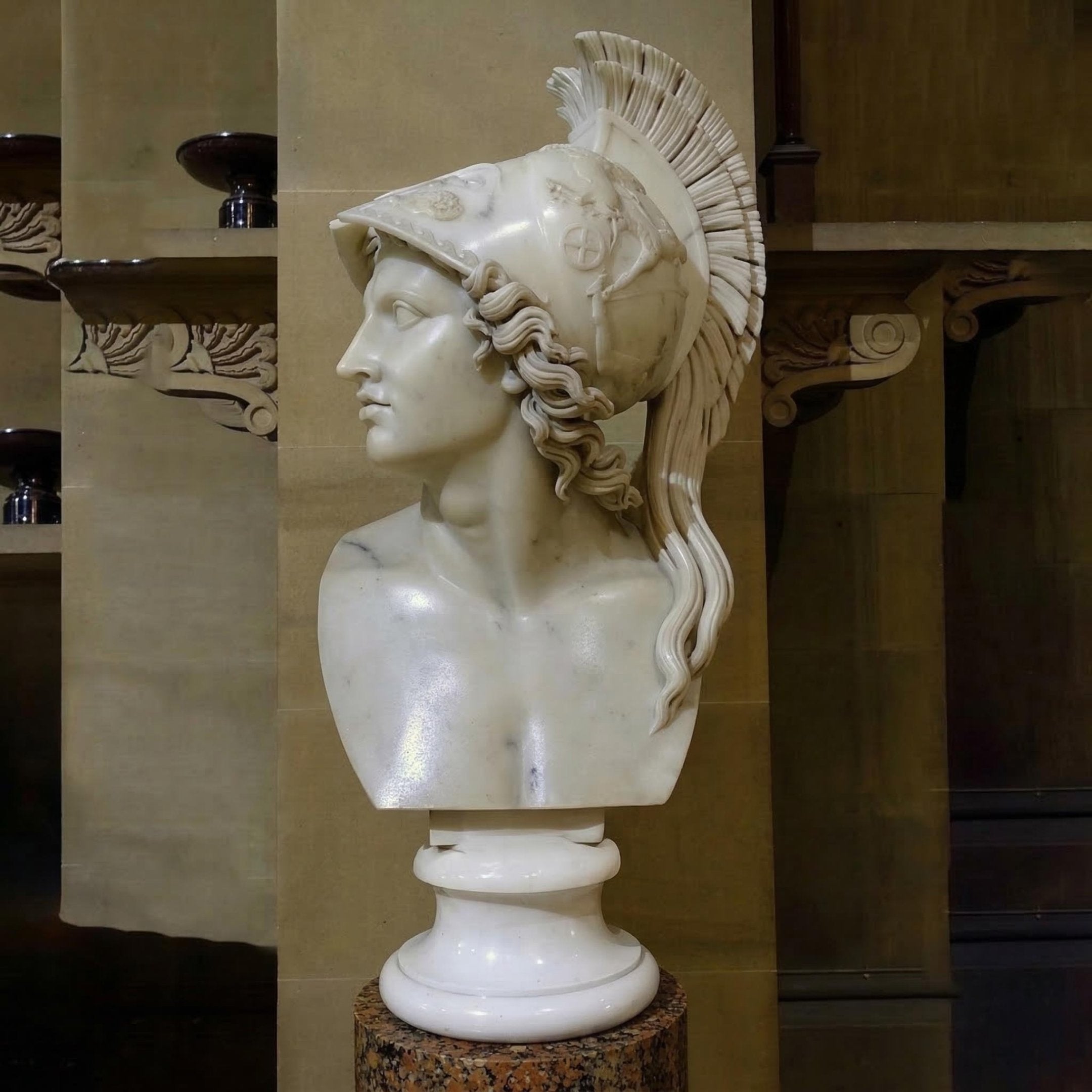 Athena Marble Bust Sculpture - 65cm by Giant Sculptures features a figure in a plumed helmet on a pedestal, set against a backdrop of classical columns and carved architectural details.