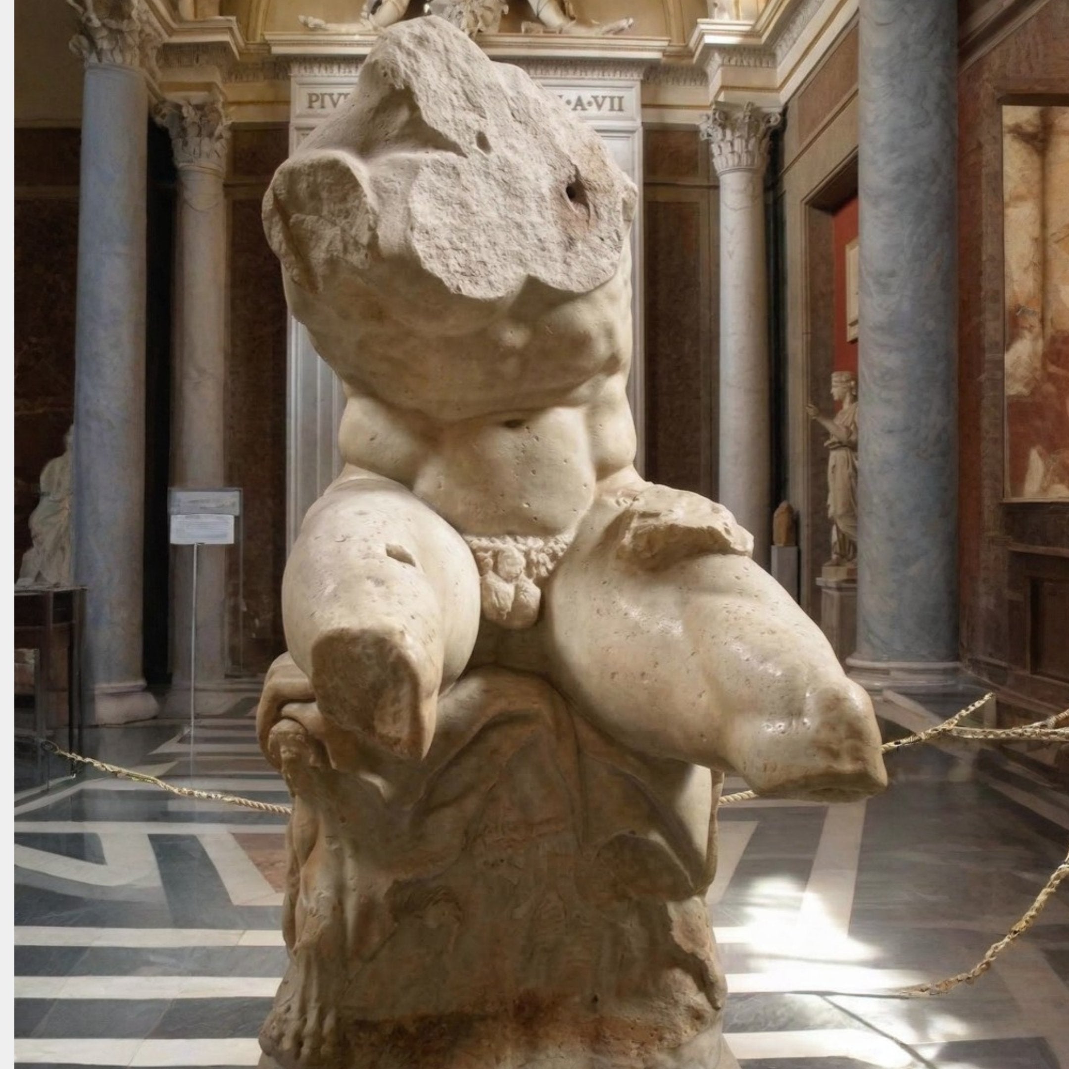The Antique Marble Torso Fragment Sculpture - 80cm by Giant Sculptures features a muscular, headless, and armless male form seated on a rock, echoing classical museum displays with columns and statues in the background.