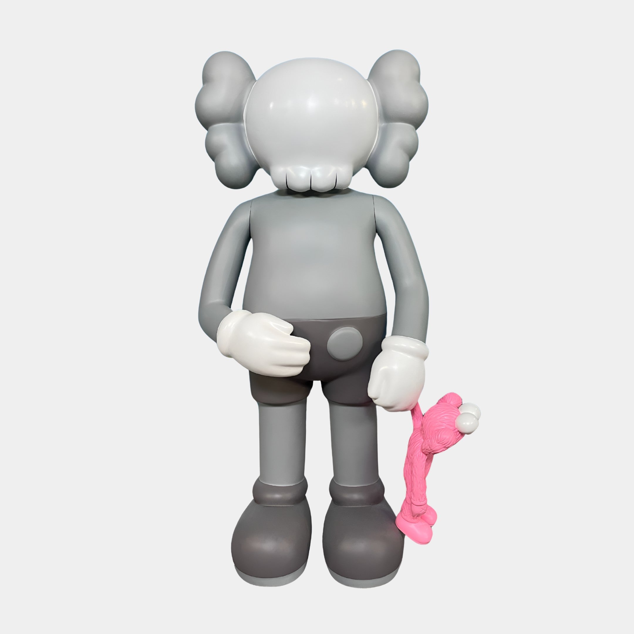 The Soft Grey Iconify Pink Furry Toy Figure by Giant Sculptures stands upright at 28cm, cartoon-like with X eyes and big gloved hands, holding a floppy pink character—ideal modern décor for any space.