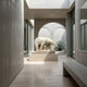 The Giant Sculptures Arctic Sentinel Bear Marble Outdoor Sculpture (160cm) stands on a pedestal in a sleek, modern space with concrete walls, arched windows, and overhead natural light. A potted agave plant is visible through an archway.