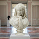 The Veiled Lady Marble Bust Sculpture - 65cm by Giant Sculptures features a woman with a delicate marble veil over her head and shoulders, perfect for display in museum galleries with classical architecture and patterned flooring.