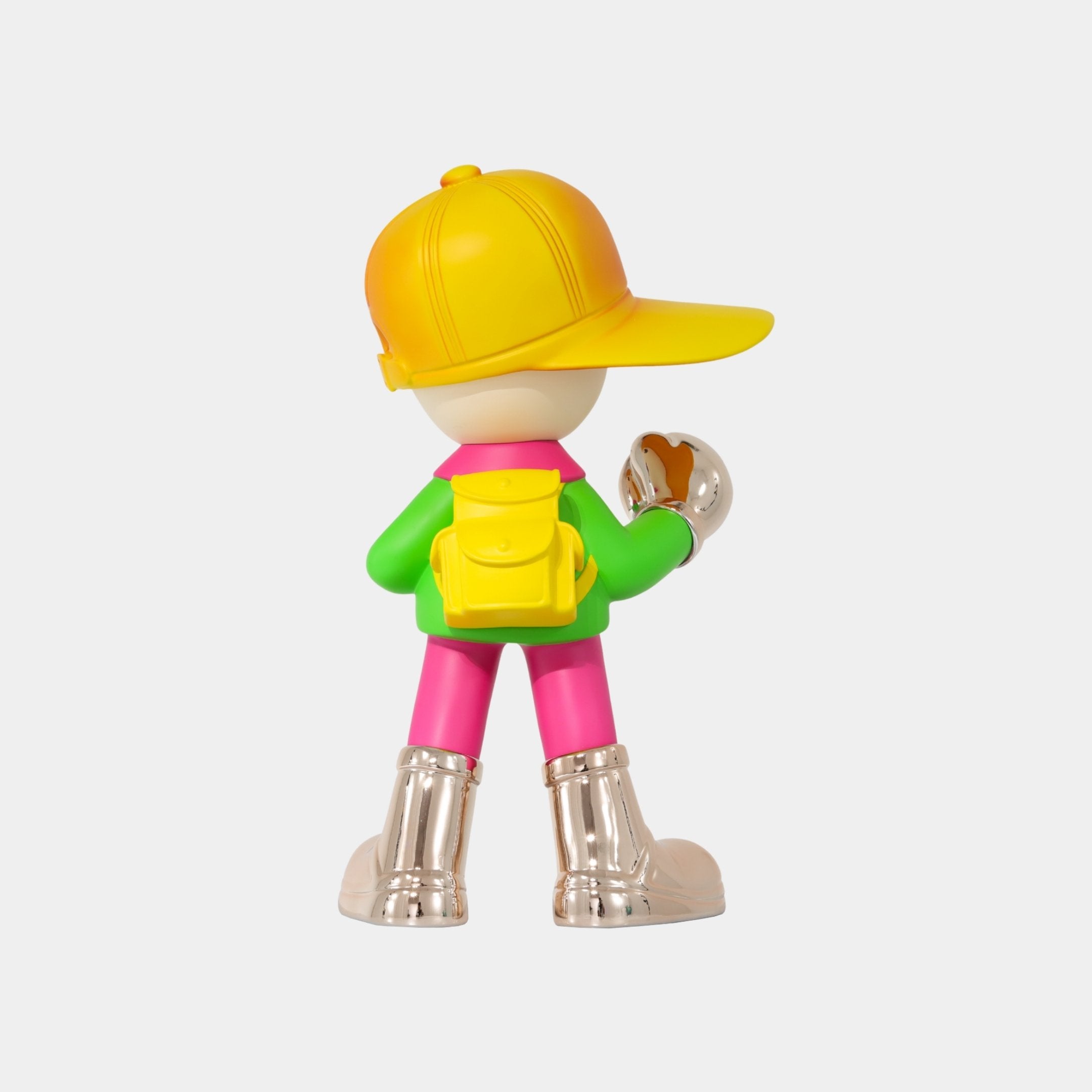 The Giant Sculptures Electroplated Boots & Fist Sunset Brimble Figure (52cm) features a colorful boy character with a yellow cap, yellow backpack, green jacket, pink pants, silver boots, and a silver object in its right hand.