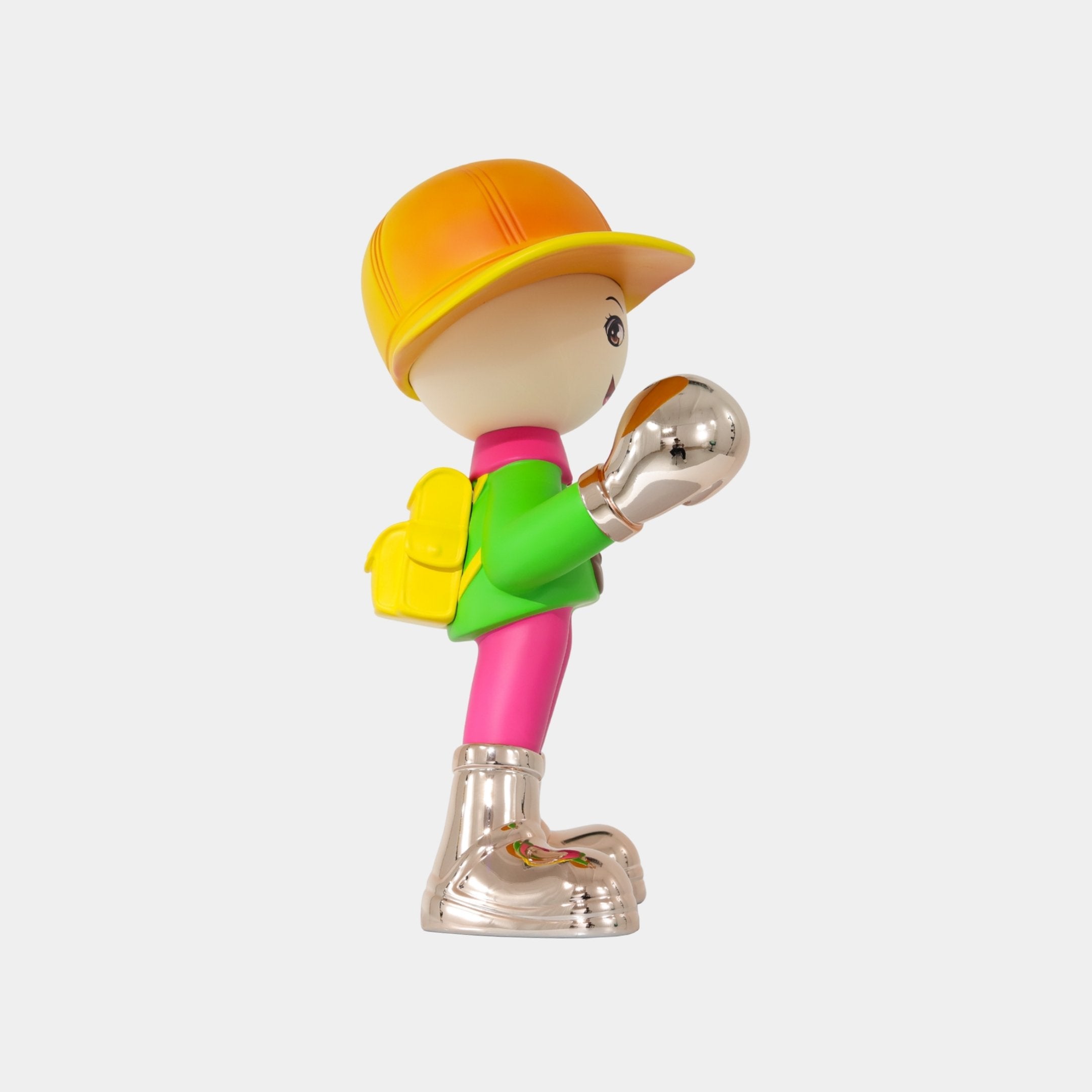 The Electroplated Boots & Fist Sunset Brimble Figure by Giant Sculptures, 52cm tall, features a decorative boy in profile wearing a yellow cap, yellow backpack, green shirt, pink pants, and shiny metallic boots on a white background.