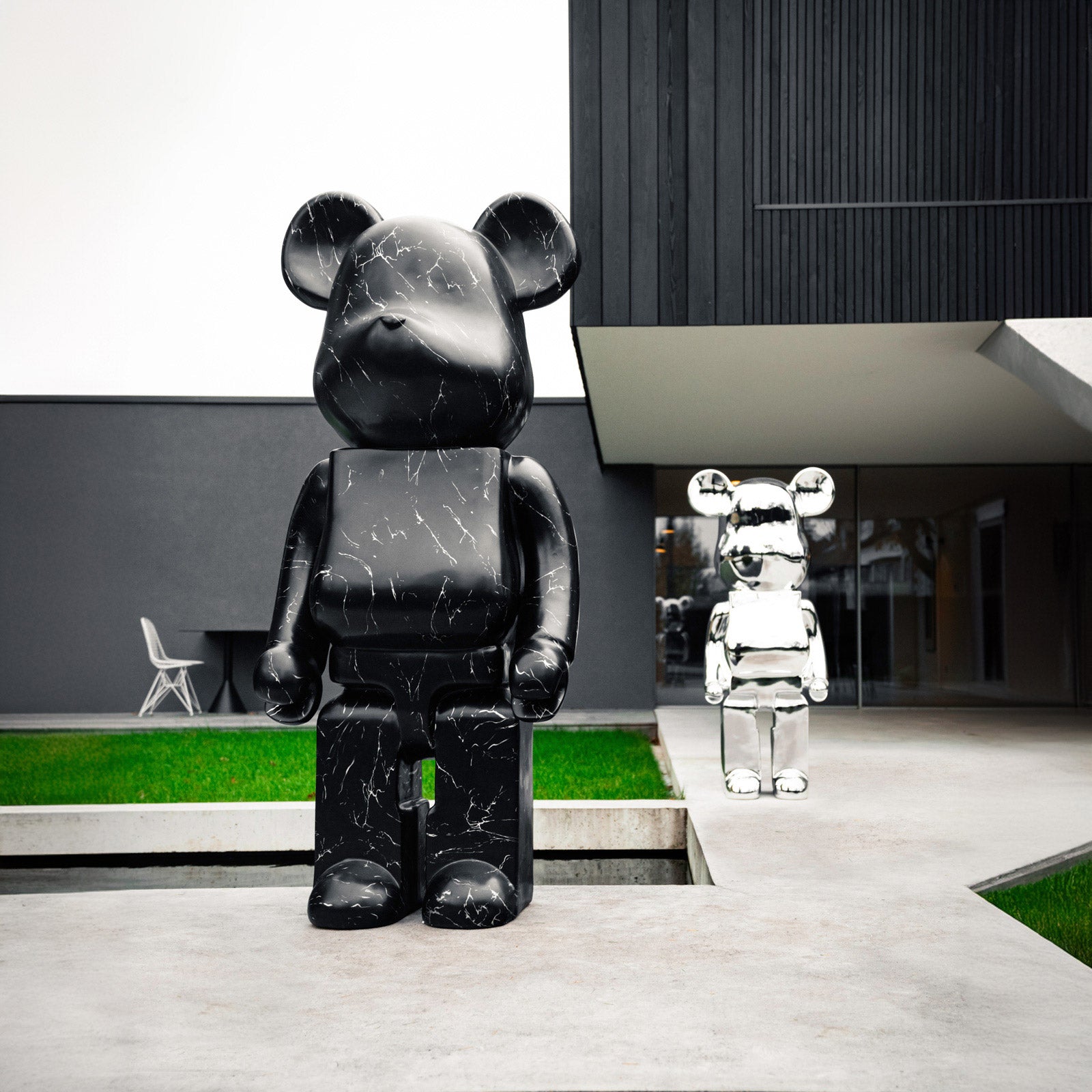 Outdoor display of black marble and chrome bear sculptures, luxury modern art in an architectural setting.