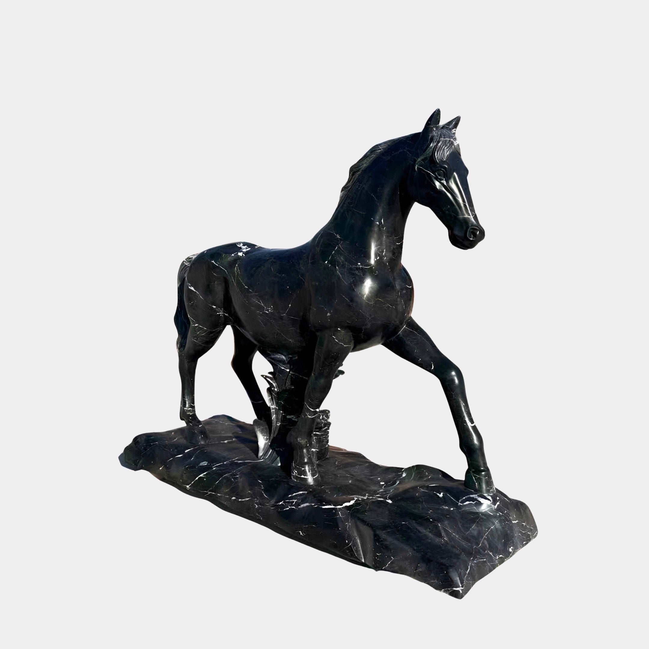 The Majestic Horse Black Marble Outdoor Sculpture by Giant Sculptures stands 220cm tall on a textured base, featuring a lifelike pose with one front leg raised. This dark marble equestrian statue is set against a plain, light-colored background.