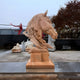 The Honeycomb Horse Head Marble Outdoor Sculpture from Giant Sculptures features dynamic, flowing details in yellow marble. With a rectangular base, it complements surrounding sculptures and trees adorned with brown leaves.