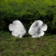 Two large Swirl-Fin Angel Fish I Marble Outdoor Sculptures by Giant Sculptures face each other on a grassy patch, with lush green foliage in the background. Crafted from marble, they feature detailed fins and expressive faces, contrasting vividly against the vibrant greenery.