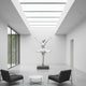A modern, minimalist room with a skylight showcases the 180cm Grace Silver Ballet Steel Sculpture by Giant Sculptures at its center, flanked by two black armchairs and a round marble table on a polished concrete floor.