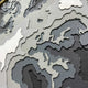 The Terranova Earth Green Round Wood Carving 3D Wall Art by Giant Sculptures features a textured, layered map design in gray, white, and black, with a stylized depiction of Europe, parts of Asia, and nearby regions.