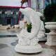 The Leaping Dolphin Marble Outdoor Sculpture by Giant Sculptures is a 150cm masterpiece depicting marine life. Its intricate design and detailed circular base make it a vibrant addition nestled among statues and lush greenery in any outdoor sculpture collection.