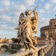 Ponte Sant Angelo V2 Angel Marble Outdoor Sculpture by Giant Sculptures, showing a winged angel in flowing drapery holding a lance, posed on the Sant'Angelo Bridge with Castel Sant'Angelo behind.