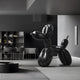 In a modern, minimalist room with dark walls and sleek furniture, the Onyx Black Balloon Dog Sculpture (80cm) by Giant Sculptures stands as a striking piece of contemporary art. The space also features a table with chairs and shelves displaying small decorative items.